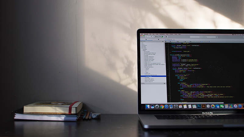 Two notebooks and a laptop displaying source code.